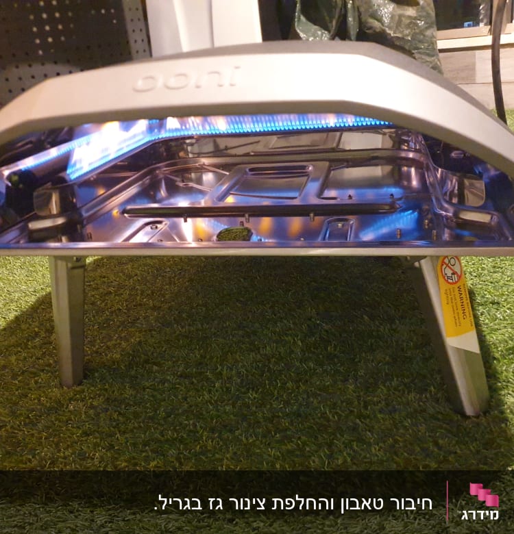 תנור גז נייד עם להבה כחולה על דשא סינתטי